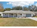 Charming single-story home featuring a well-maintained lawn, attached garage, and cozy covered front porch at 1517 New Abbey Ave, Leesburg, FL 34788