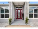 Inviting front entryway showcasing a red door, brick accents, and decorative plants at 6215 Se 13Th St, Ocala, FL 34472