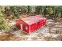 Exterior shot of a vibrant red outbuilding with a metal roof and a single door and window at 7670 Se 110Th Street Rd, Belleview, FL 34420