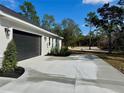 Attached two-car garage featuring a paved driveway, fresh landscaping, and exterior lighting at 8481 Sw 137 Ct, Dunnellon, FL 34432