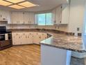 Well-lit kitchen with white cabinets, wood-look tile floor, and stainless steel appliances at 8639 Sw 116Th Lane Rd, Ocala, FL 34481