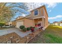 Charming two-story home with a two car garage, beautiful landscaping, and a walkway to the front door at 12312 Ne 48Th Loop, Oxford, FL 34484