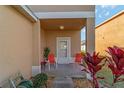Covered front porch features neutral tones, two red chairs, and green landscaping at 12312 Ne 48Th Loop, Oxford, FL 34484