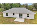 Rear view of a white one-story home showcasing a sliding glass door and small concrete patio at 13743 Sw 113 Ln, Dunnellon, FL 34432