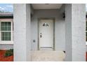 Inviting entryway showcasing a white front door, gray walls, and manicured landscaping details at 13757 Sw 113 Ln, Dunnellon, FL 34432