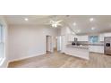 Bright, open-concept living space with modern light wood floors, white walls, and a ceiling fan at 24237 Sw South Lakes Ct, Dunnellon, FL 34431