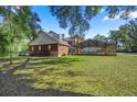 Expansive backyard featuring a screened pool, brick home, and a black metal fence at 4940 E Fort King St, Ocala, FL 34470