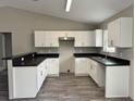 Modern kitchen features white cabinets, sleek black countertops, and new appliances, offering a stylish cooking space at 1 Fisher Lane Way, Ocklawaha, FL 32179