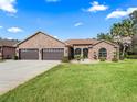 Attractive single-story home featuring a stone facade, lush green lawn, and a convenient three-car garage at 11084 Se 168Th Loop, Summerfield, FL 34491