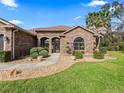 Inviting stone-clad home showcasing arched entryways, manicured landscaping, and a welcoming walkway at 11084 Se 168Th Loop, Summerfield, FL 34491