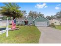 Home exterior featuring manicured lawn, tidy landscaping, a concrete driveway, and an American flag at 11725 79Th Cir, Ocala, FL 34476