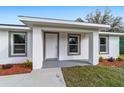 A close-up view of the covered front porch with gray trimmed windows and landscaping at 15123 Se 63Rd Ct, Summerfield, FL 34491