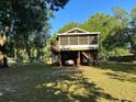 A raised home with a charming porch sits on a grassy lot surrounded by mature trees at 2851 Ne 162Nd Ln, Citra, FL 32113