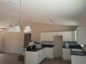 New kitchen with white cabinetry, black countertops, and a stylish pendant light fixture at 46 Malauka Dr, Ocklawaha, FL 32179