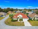 Aerial view of a yellow single-story home featuring a red tile roof, well-manicured lawn, and brick-paved driveway at 7451 Sw 111Th Pl, Ocala, FL 34476