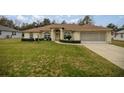 Charming home featuring a well-manicured lawn, arched windows, and a spacious two-car garage at 10884 Sw 53Rd Cir, Ocala, FL 34476