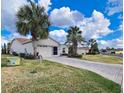 Property featuring a brick paver driveway, a two-car garage, and lawn with mature palm trees at 15857 Sw 11Th Terrace Rd, Ocala, FL 34473