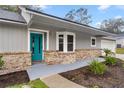 A covered front porch showcasing a teal front door and decorative brick accenting at 6 Cherry Drive Ln, Ocala, FL 34472