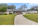 Charming home featuring a teal door, well-manicured lawn, and an attached two car garage at 6 Cherry Drive Ln, Ocala, FL 34472