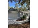 Attached two-car garage and a tidy landscape design along the side of the house at 8045 Sw 115Th Loop, Ocala, FL 34481