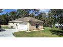 View of the home's back exterior and garage, featuring a well-maintained lawn and landscaping at 8498 Sw 129Th Terrace Rd, Dunnellon, FL 34431