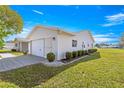 Attached two-car garage with a well-maintained lawn and landscaping at 9884 Se 175Th Pl, Summerfield, FL 34491