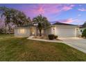 Charming single-story home with a two-car garage, landscaped front yard, mature trees, and a beautiful dusk sky at 2251 Nw 50Th Ave, Ocala, FL 34482