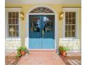 Charming entryway with striking blue-green double doors, decorative windows, and elegant sconces, framed by potted plants at 2775 Sw 53Rd St, Ocala, FL 34471