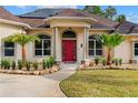 Inviting front entrance featuring a red door, decorative columns, and lush landscaping at 32 Allenwood Look, Ormond Beach, FL 32174