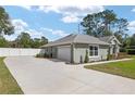 The home features a spacious driveway leading to a two-car garage and a backyard enclosed by a white fence at 5297 Se 39 Loop, Ocala, FL 34480