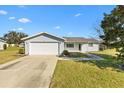 Inviting single-story home with an attached two-car garage, manicured lawn, and concrete driveway on a sunny day at 10255 Se 178Th Pl, Summerfield, FL 34491