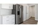 Close-up of stainless steel refrigerator, white cabinets and wood-look floors in bright kitchen at 2746 Sw 147Th Ct, Ocala, FL 34481