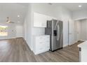 Bright kitchen with white cabinets, stainless steel refrigerator, and stylish gray wood-look flooring at 2746 Sw 147Th Ct, Ocala, FL 34481