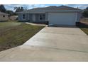 A long concrete driveway leads to the attached garage of this single story home at 28 Pine Trace Run, Ocala, FL 34472