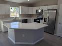 Bright kitchen featuring white cabinets, an island, modern appliances, and neutral countertops at 28 Pine Trace Run, Ocala, FL 34472