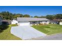 Aerial shot of the single-story home featuring a lush green yard, long driveway, and a classic brick exterior at 3853 Se 60Th St, Ocala, FL 34480