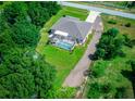 Aerial shot of a home with a screened-in pool, surrounded by greenery and a gravel driveway at 4160 Sw 98Th St, Ocala, FL 34476