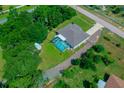 Home's backyard view showcases a screened-in pool surrounded by trees, and gravel driveway at 4160 Sw 98Th St, Ocala, FL 34476