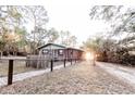 Exterior view of cabin-style home with fenced yard and sunlit clearing at 5526 Se 170Th Ct, Ocklawaha, FL 32179