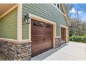 A two-car garage featuring wood doors and stone accents, complementing the home's exterior at 5995 Se 22Nd Ave, Ocala, FL 34480