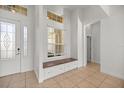 Bright foyer featuring tile floors, a bench seat with storage, and a decorative glass front door at 10138 Lake Miona Way, Oxford, FL 34484