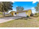 A yellow home with well-maintained landscaping, a paved driveway, and a two-car garage at 11620 Sw 84Th Avenue Rd, Ocala, FL 34481