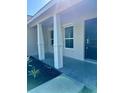 Covered entryway featuring white columns, dark door, and concrete porch at 13936 Sw 113 Ln, Dunnellon, FL 34432