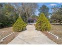 Charming single-story home with a red metal roof, bright red doors, with mature trees at 23761 Sw Plaza Ct, Dunnellon, FL 34431