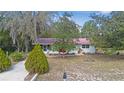 Charming single-story home with a red metal roof, bright red doors, and mature landscaping at 23761 Sw Plaza Ct, Dunnellon, FL 34431