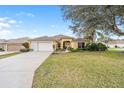 Charming yellow single Gathering home with a two-car garage and a well-manicured lawn at 3001 Rugby Way, The Villages, FL 32162