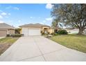 Charming yellow single Gathering home with a two-car garage, a well-manicured lawn and blue sky at 3001 Rugby Way, The Villages, FL 32162