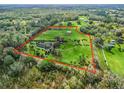 Overhead view of estate featuring lush pastures outlined in red, mature trees, and residence at 6994 Nw 320 Hwy, Micanopy, FL 32667