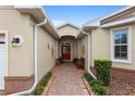 Covered entryway with brick paving, leading to a vibrant red front door and decorative wall accents at 9274 Sw 94Th Loop, Ocala, FL 34481