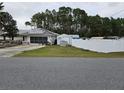 Exterior view of home, featuring white fence, a shed, and a screened-in garage at 11 Pecan Pass Loop, Ocala, FL 34472